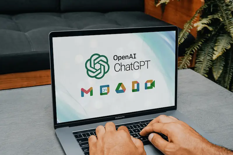 Laptop affichant le logo OpenAI ChatGPT et les icônes Google Workspace, symbole intégration IA et outils productivité.