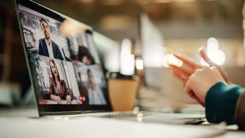 Vidéoconférence professionnelle avec plusieurs participants sur écran d'ordinateur portable au bureau.