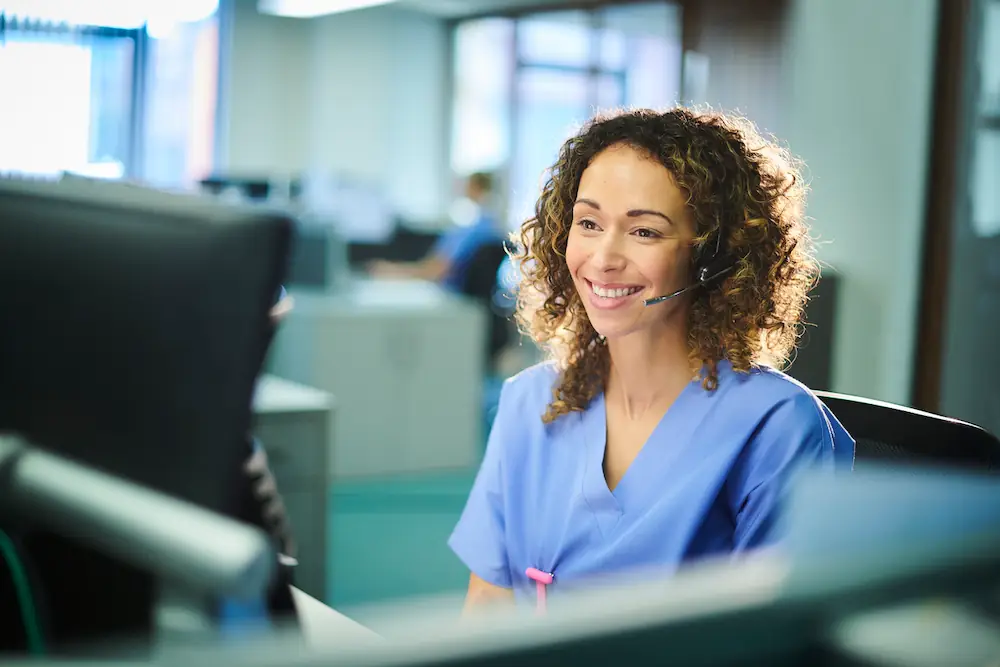 Professionnelle de santé souriante avec casque au poste de travail en environnement médical moderne.