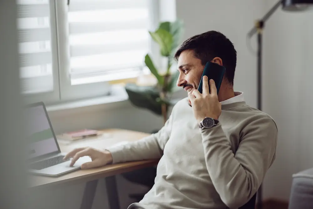 Homme d'affaires travaillant à son bureau avec laptop, téléphonant pour une réunion professionnelle en ligne.